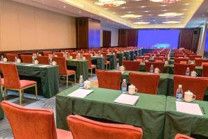 a conference room with tables and chairs and a screen at Riverside International Hotel in Wuzhou
