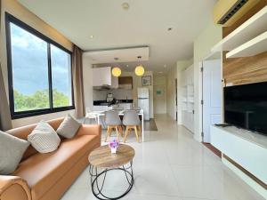 una sala de estar con un sofá y una mesa en Cozy 2 Bedrooms - The Lago Nai Harn by AHP, en Rawai Beach