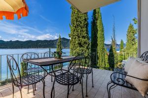 a table and chairs on a balcony with a view of the water at Panoramic Lake View Apartments with Pool & Breakfast in Torri del Benaco