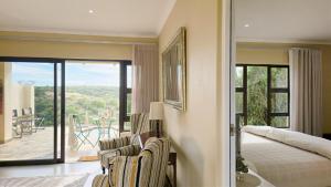 a bedroom with a bed and a balcony with a patio at Hitgeheim Garden Cottages in Addo