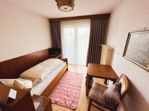 Un dormitorio con una cama y una mesa y una ventana. en Gasthof Söll, 