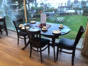 a black table with chairs and a table with hats on it at The Great Western B&B in Paignton