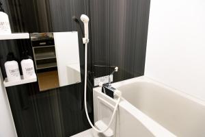 ein Badezimmer mit Badewanne und Spiegel in der Unterkunft Hotel Small World in Hiroshima + 7 Fotos