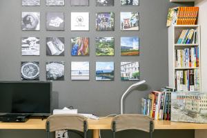 ein Schreibtisch mit einem Computer und einigen Bildern an der Wand in der Unterkunft Hotel Small World in Hiroshima