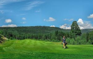 a woman walking in a field of green grass at Nice cabin at Norefjell skicenter in Noresund