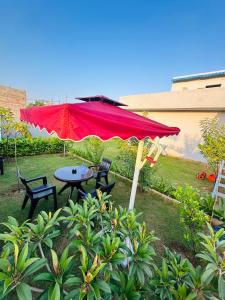 une table et des chaises sous un parapluie rouge dans l'établissement Ekant The Luxury Farm, à Jaipur
