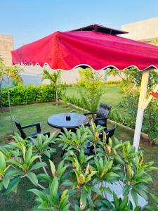 une table et des chaises sous un parapluie rouge dans l'établissement Ekant The Luxury Farm, à Jaipur 8 autres photos