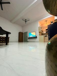 un salon avec un sol blanc et une télévision à écran plat dans l'établissement Ekant The Luxury Farm, à Jaipur