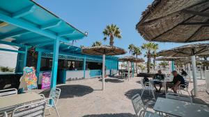 een groep mensen die aan een tafel zitten met parasols bij Playa y Palmera in Corralejo