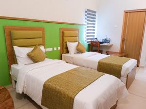two beds in a room with a green wall at tan90 Comfort Stays in Tiruchirappalli