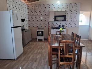 a kitchen with a table and chairs and a refrigerator at Casa vila costeira Guriú piso superior in Guriú