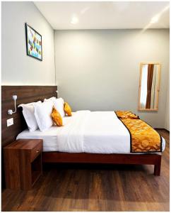 a bedroom with a bed with white sheets and orange pillows at DEWALING by Laughing Lama Hotels in Phuntsholing