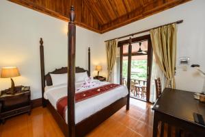 a bedroom with a bed and a desk and a window at Treasure Heritage Hotel in Luang Prabang +77 photos