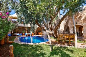 a swimming pool in a yard with trees and chairs at La Cabane Marocaine in Essaouira