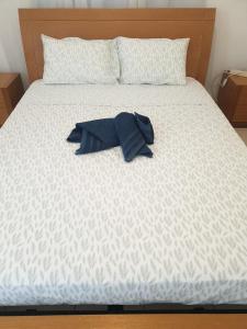 a white bed with a blue shirt on it at 1 bedroom in Regina Gardes 2 in Paphos City