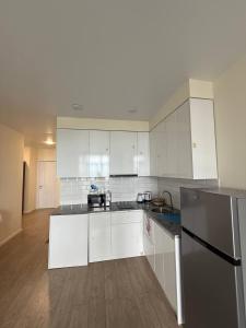 Una cocina con gabinetes blancos y encimeras negras. en Rihlaa aprt c 1105, en Itʼkhvisi