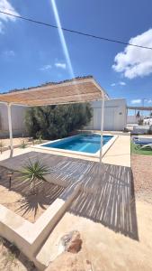a swimming pool with a wooden pergola at Mediterranean house in Djerba Midoun in Taguermess