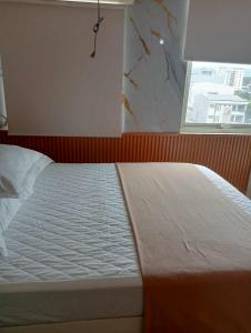 a bedroom with a white bed with a window at Holland Park in Biñan