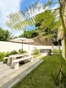 un giardino con panchina e ombrellone di Central house with 2 large bedrooms a Kuta Lombok