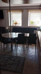 Un comedor con mesa y sillas y dos ventanas. en Dom Kopernika 4, en Chełm