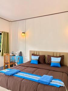 a bedroom with a large bed with blue pillows at Khao Sok Backpacker Hostel in Khao Sok