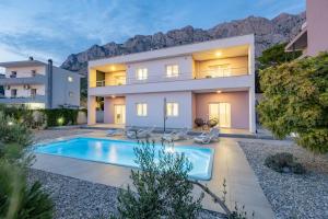a villa with a swimming pool in front of a house at VILLA VIS MARIS in Makarska