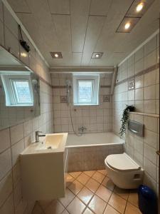 a bathroom with a tub and a toilet and a sink at Shakina Residences near Frankfurt Airport in Rüsselsheim