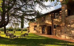 a building with chairs and a table in the grass at Assisi Villa Simi in Petrignano