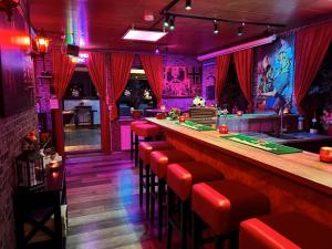a bar with red stools in a nightclub at Gruppenunterkunft-Klein-Holland-Harz-aussergewoehnlich-und-einzigartig-mit-grossartiger-Unterhaltung-fuer-jedes-Alter-fuer-bis-zu-24-Personen in Herzberg am Harz