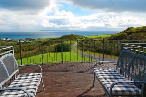 two benches sitting on a balcony looking at the ocean at Ocean View Lodge in Kilchiaran +1 photo