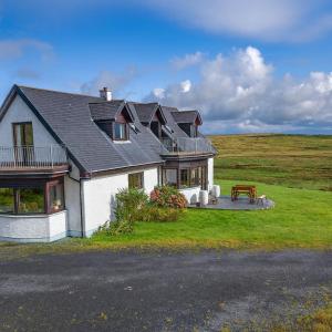 a large house with a bench on a field at Ocean View Lodge in Kilchiaran