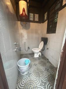 a bathroom with a toilet and a bucket in it at Isabella Hostel in Shillong