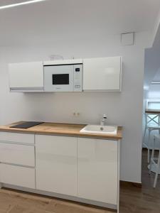 a white kitchen with a sink and a microwave at Apartamento BANDERILLAS - Hotel Ruta del Segur in Pontones