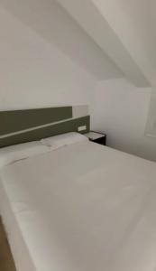 Una cama blanca con cabecera verde en una habitación. en Apartamento BANDERILLAS - Hotel Ruta del Segur, en Pontones