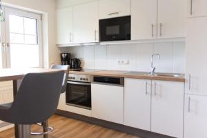 a kitchen with white cabinets and a sink at Knipper RE24 in Sögel