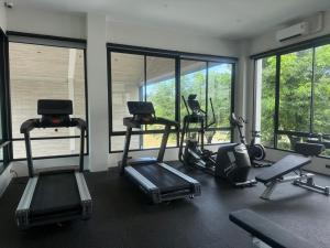a gym with treadmills and ellipticals in a room with windows at Modern 1 & 2 Bedroom Apartments Naiyang Phuket by Mango Family in Nai Yang Beach