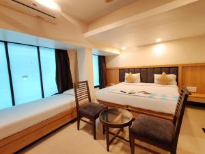 a bedroom with a bed and a table and chairs at Hotel Aishwarya Residency in Nerul +29 photos