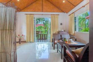 a living room with a table and chairs and windows at The Green Oasis Resort in Ban Rong