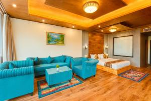a living room with a blue couch and a bed at Rockland Cottage Manali - Centrally Heated & Air Cooled Premium Rooms in Manāli