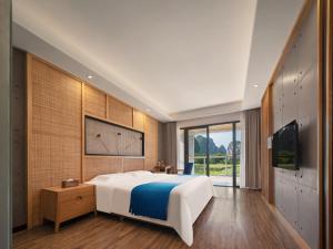 a bedroom with a large white bed and a television at Yangshuo Zen Garden Resort - Rich Chinese traditional activities in Yangshuo