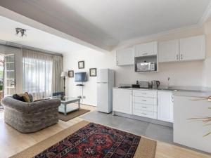 a kitchen with white cabinets and a couch in a room at Emmarentia Guest House in Johannesburg