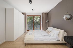 a white bedroom with a bed and a window at Luxurious Apartment with a Terrace and Garage - Grzybowska in Warsaw