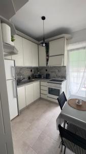 a kitchen with white cabinets and a table and a table and a table at Sun day Apartment in Paralia Katerinis