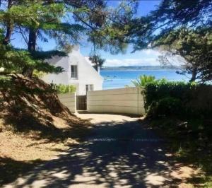 a driveway leading to a white house with a view of the water at BB les pieds dans L'eau CARANTEC in Carantec