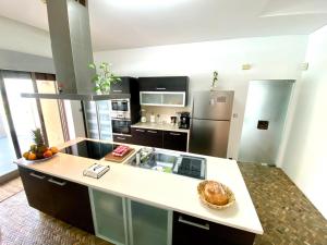 a large kitchen with a large white counter top at Villa les escapades luxo & piscine 