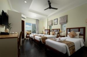 a hotel room with four beds and a table at Grand Bayon Siem Reap Hotel in Siem Reap