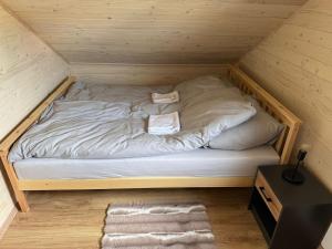 ein kleines Bett in einem Holzzimmer mit Holzboden in der Unterkunft Domek z jacuzzi i kominkiem - cisza, natura, relaks 