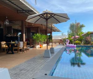 a swimming pool with an umbrella next to a restaurant at Kalamung Resort and Pool villas in Ao Nang Beach