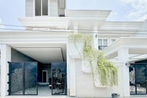 a white house with black doors and a plant at Urbanview Hidayah Living Syariah Balekambang Manahan in Bonorejo