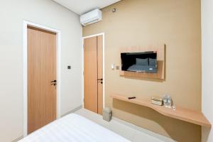 a bedroom with a bed and a tv on the wall at Urbanview Hidayah Living Syariah Balekambang Manahan in Bonorejo